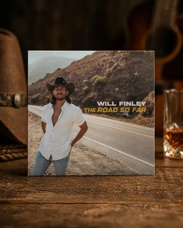 Signed Will Finley The Road So Far CD on a wooden bar with a leather hat and whiskey glass
